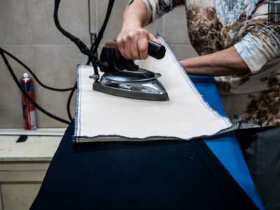 Rosaria, stiratrice da 42 anni ci svela un segreto del mestiere mentre � all�opera con un pantalone: �� preferibile stirare l�indumento o al rovescio o con un panno provvisto di ret�na che funga da isolante�